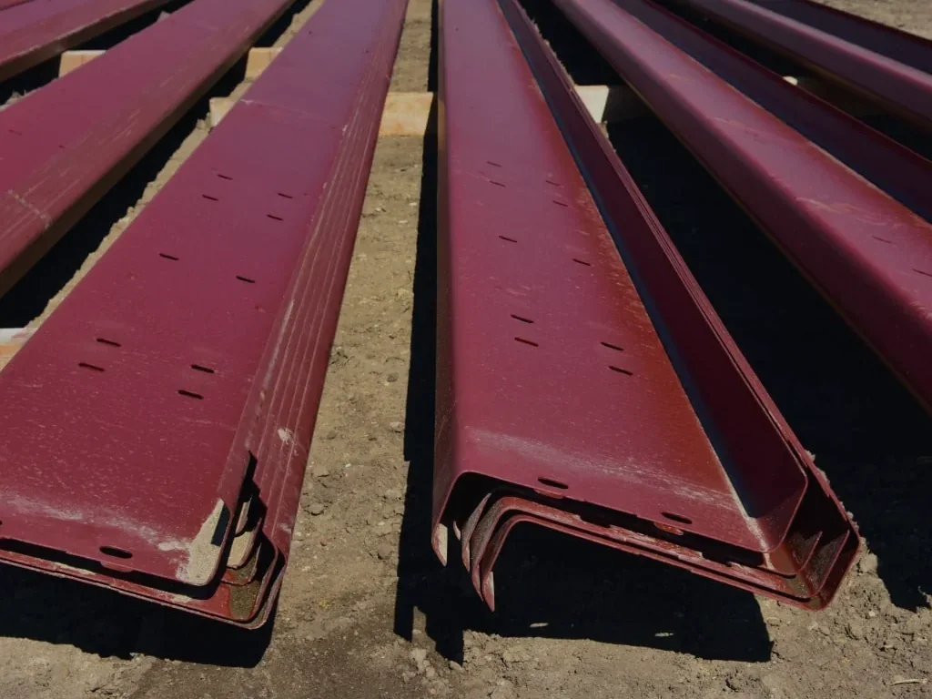 Red oxide Z purlins stacked at the yard, profile ends facing the camera