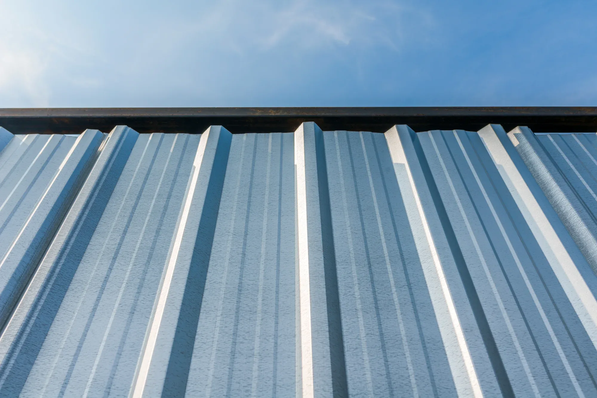 Ribbed R-Panel metal wall rising into a blue sky