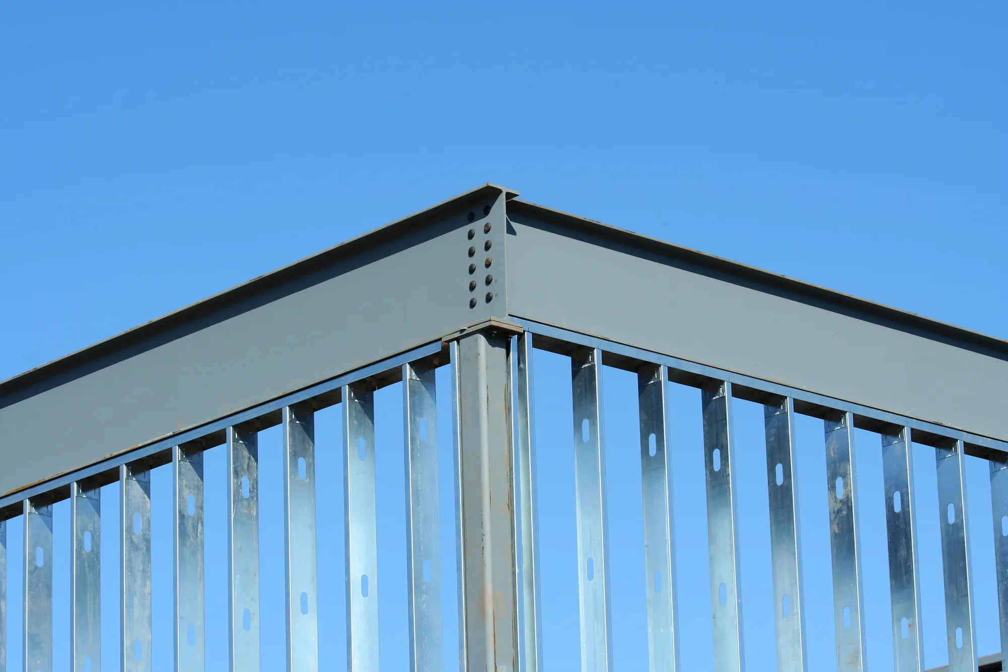 Postes de acero perforados y viga contra un cielo azul